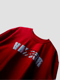 A close-up of a red crewneck t-shirt featuring a distressed white graphic text print that reads 'VALOUR' with a red claw-slash design underneath, set against a plain light gray background.