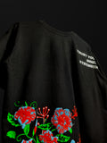 close-up detail of black oversized t-shirt texture featuring a bottom red and green floral graphic and white "TRUST YOUR INNER STRENGTH" text