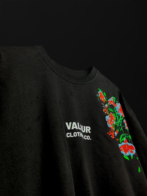 close-up detail of black oversized t-shirt texture featuring a side panel red and green floral graphic and white Valour Clothing Co.