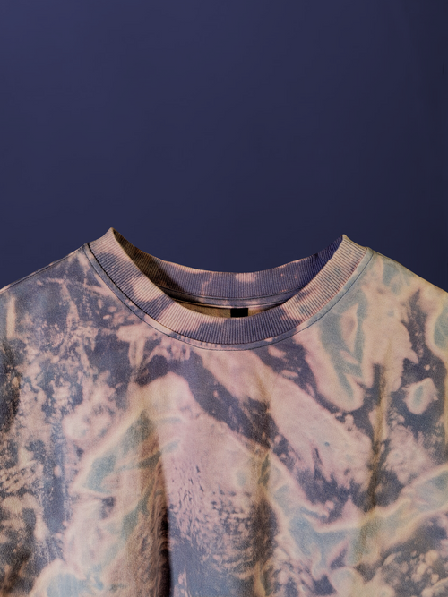 close-up detail of the crewneck and purple blue tonal acid wash pattern on an oversized cotton t-shirt