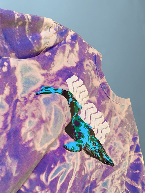 close-up of purple and blue acid wash oversized t-shirt with unique flying whale or bird graphic in teal and white puff print texture