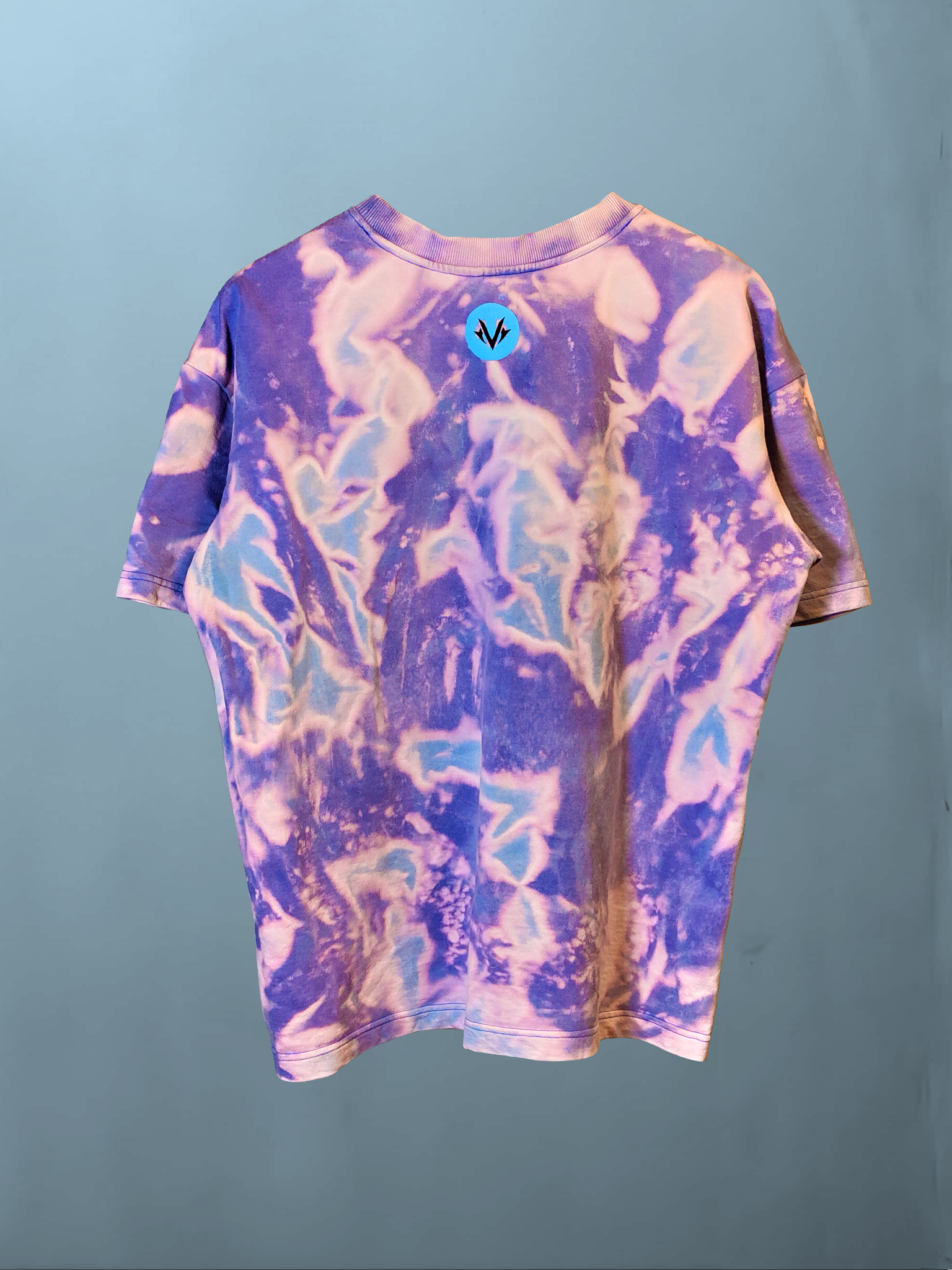 full back view of the purple and blue acid wash oversized t-shirt, highlighting the unique bleach pattern and small round neon blue logo at the neckline