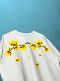 white oversized t-shirt with large yellow and red floral graphic across the chest, featuring a textured cotton terry fabric